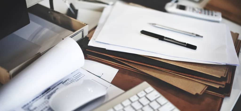 A stack of documents scattered across a desk.